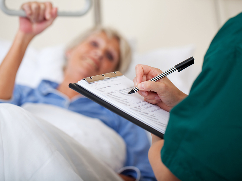 Mid,Adult,Female,Nurse,Writing,On,Clipboard,While,Looking,At