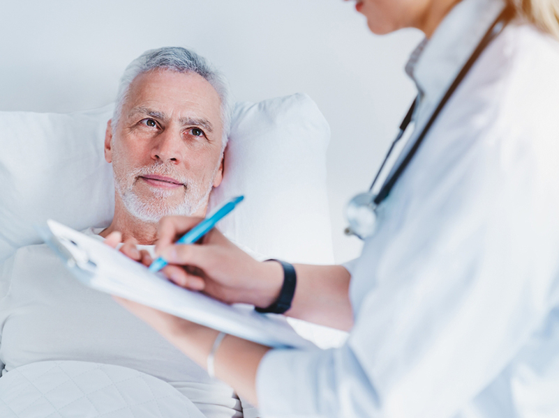 Senior,Man,With,Female,Doctor,Writing,To,Clipboard,At,Hospital