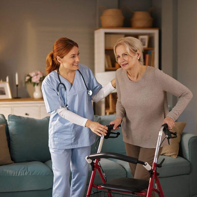 A,Young,,Red-haired,Caregiver,In,Blue,Scrubs,Assists,An,Elderly